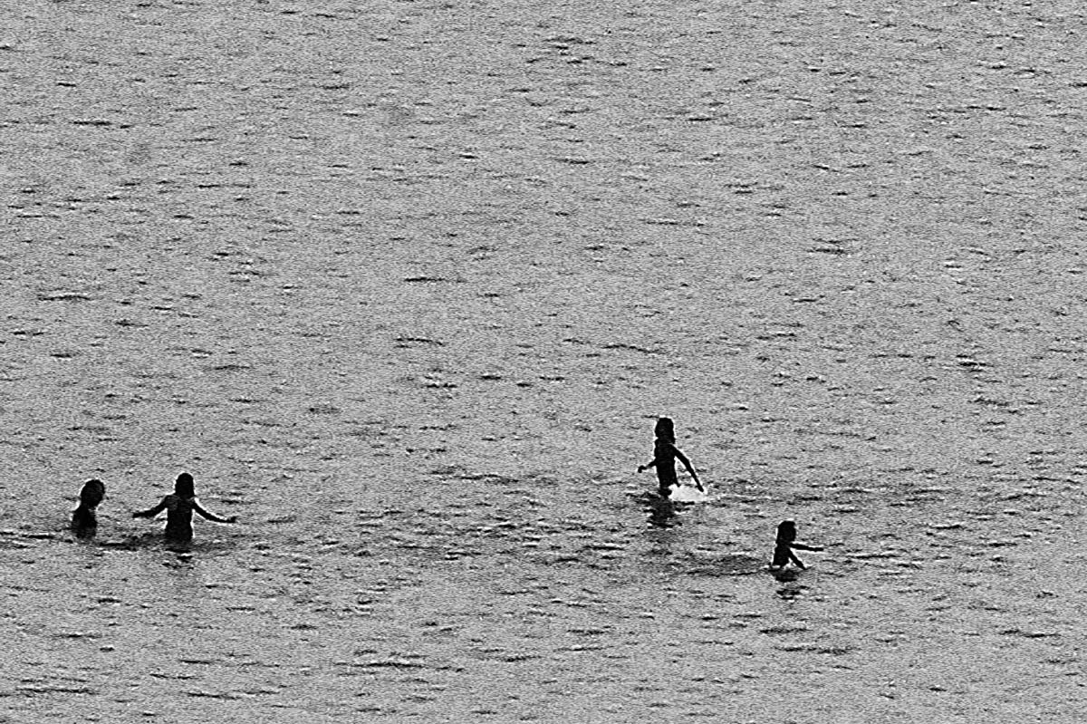 The blurred silhouettes of children playing in the water on a beach in Brittany in the summer, from the series Another summer by Emmanuel Pineau