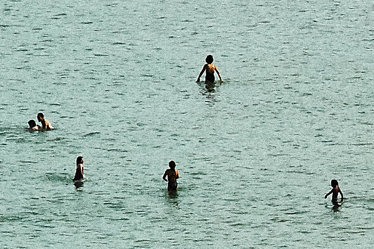 Blurry silhouettes of people in the water on a beach in Brittany in the summer, from the series Another summer by Emmanuel Pineau