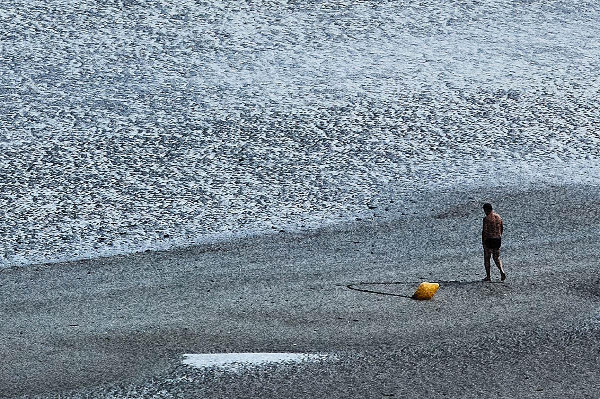 The blurred silhouette of a man walking towards the sea on a beach in Brittany in summer, from the series Another summer by Emmanuel Pineau