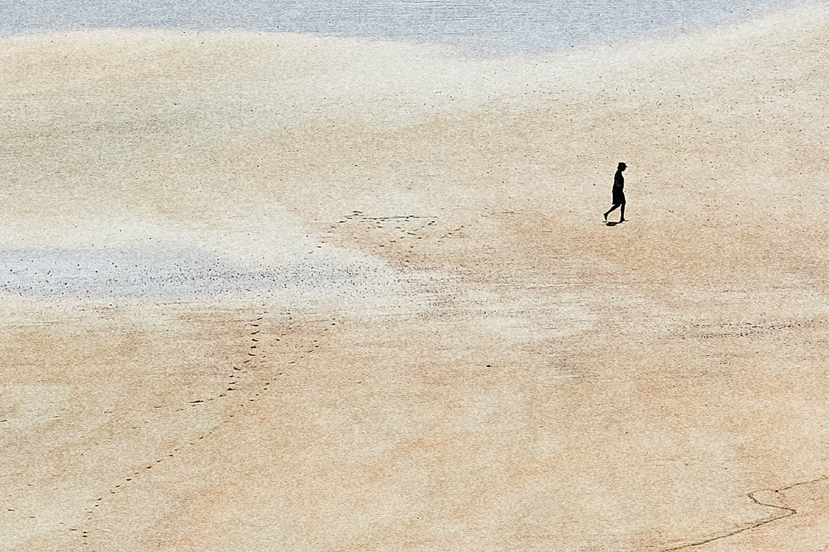 The blurred silhouette of a woman walking in profile on the sand of a beach in Brittany in summer, from the series Another summer by Emmanuel Pineau