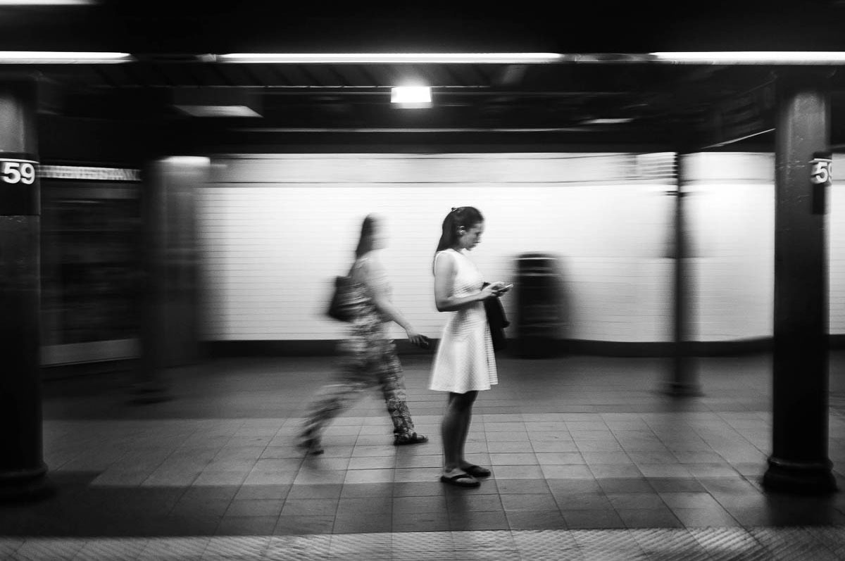 A woman in a white dress waiting on the subway platform in New York, from the series Going Underground by Emmanuel Pineau