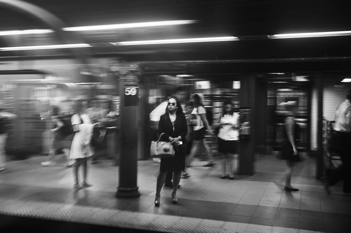 A woman wearing dark glasses waits on the subway platform in New York, from the series Going Underground by Emmanuel Pineau