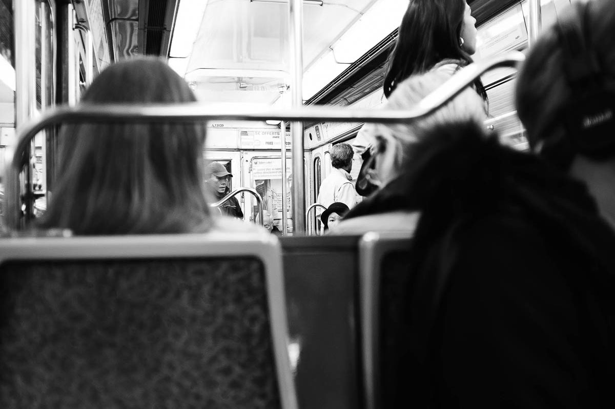 A woman wearing a black hat is sitting in a Paris metro train, from the series Going Underground by Emmanuel Pineau
