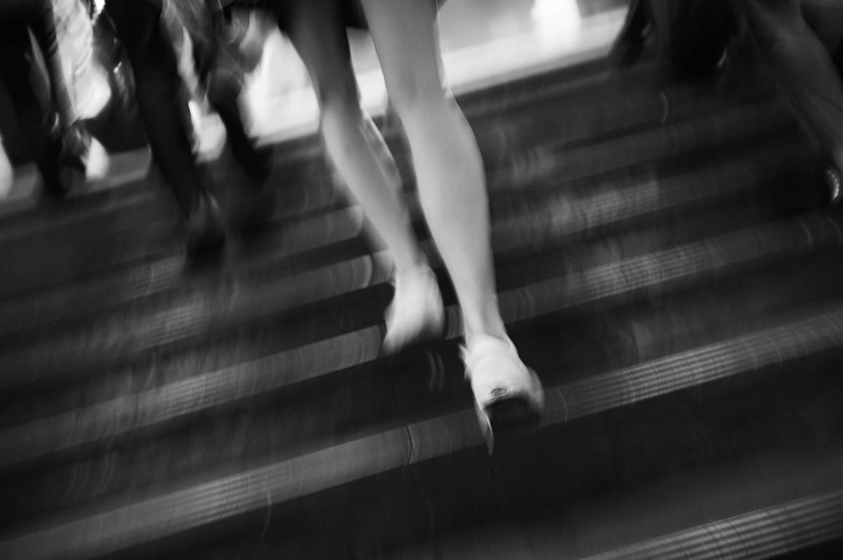 The legs of a woman in a skirt climbing stairs in the Paris metro, from the series Going Underground by Emmanuel Pineau