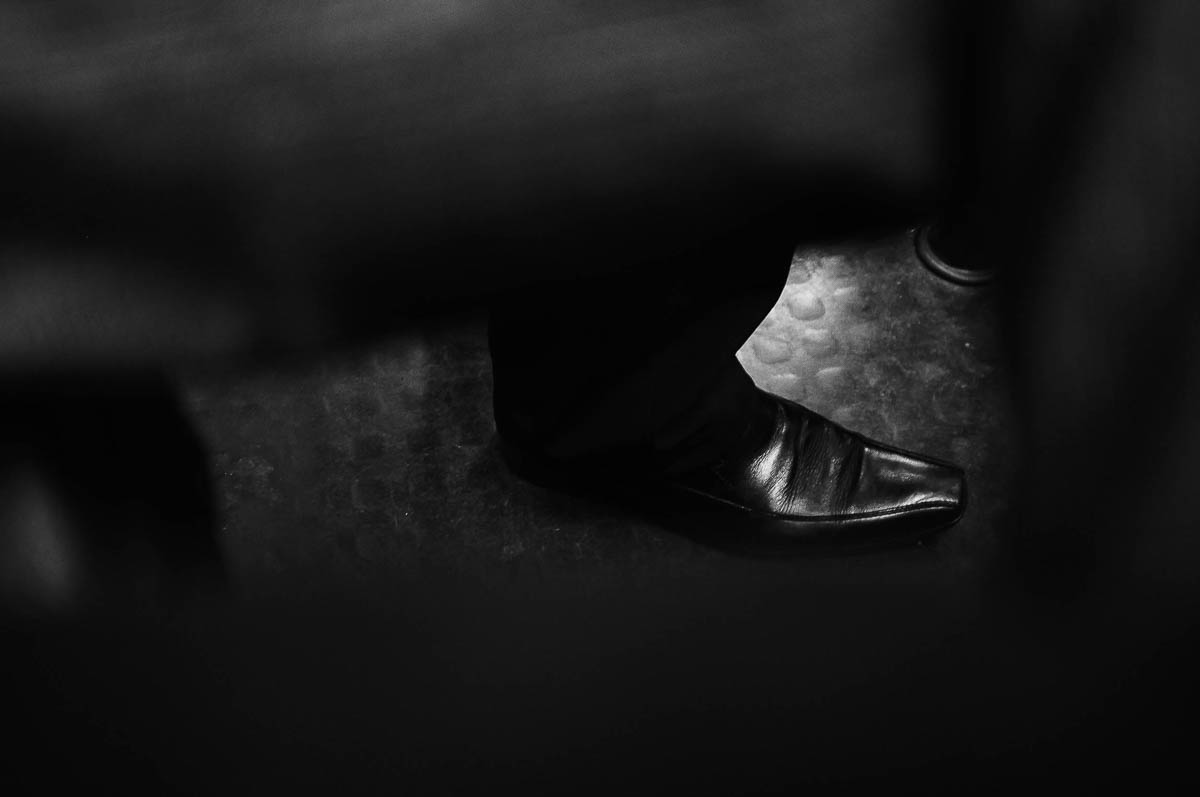 Close-up of a black shoe on a man standing in a Paris subway car, from the series Going Underground by Emmanuel Pineau