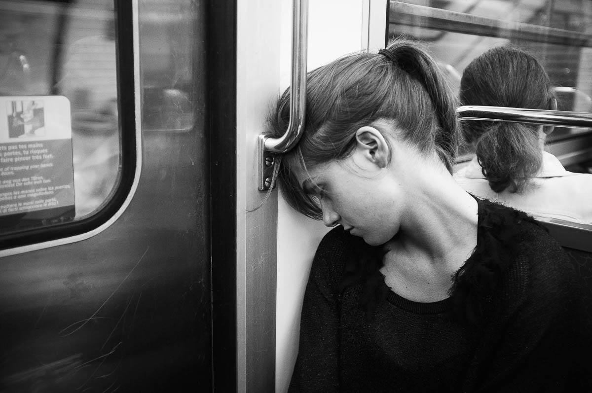A young woman sleeps sitting up in a subway car in Paris, from the series Going Underground by Emmanuel Pineau