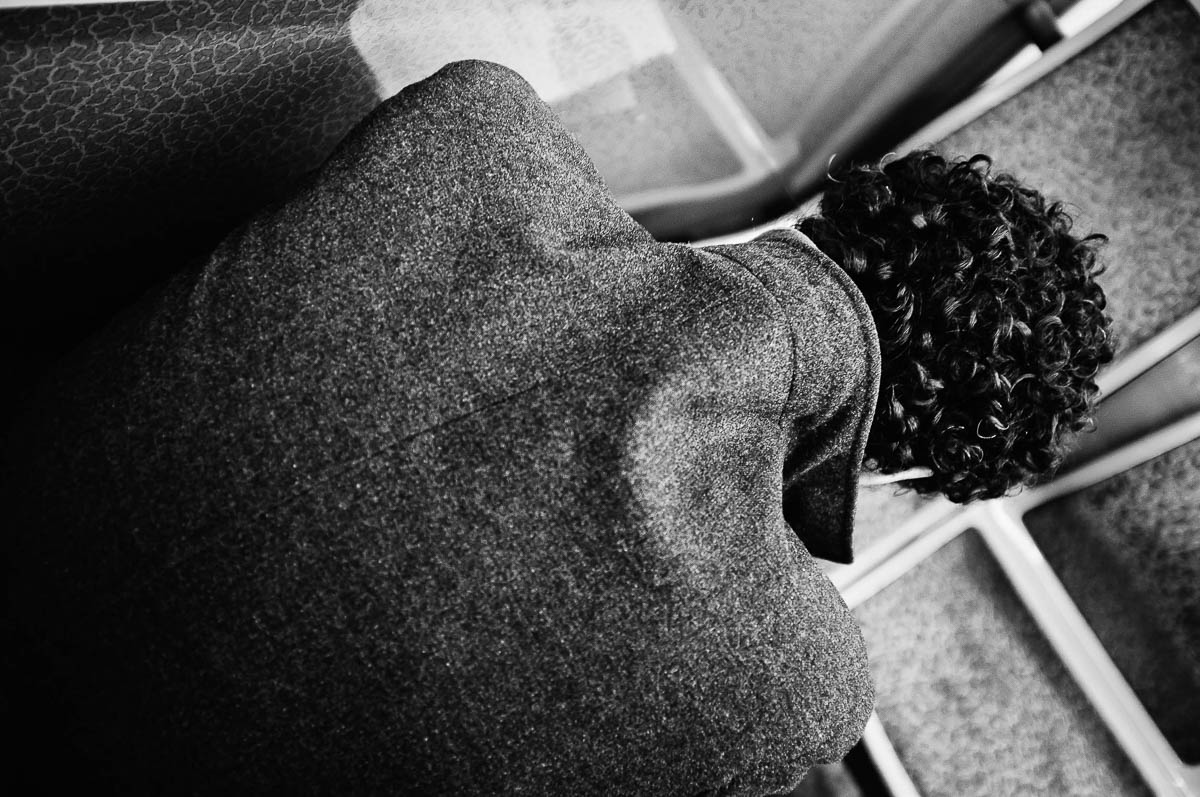 A man with his back to us, sitting in a Paris metro train and wearing a grey coat with the collar turned up, from the series Going Underground by Emmanuel Pineau