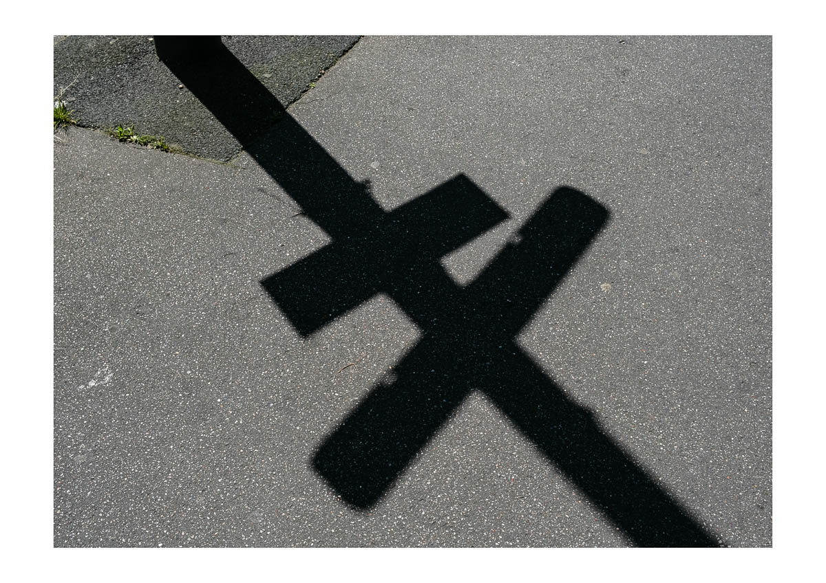 The shadow of a road sign on the asphalt, from the series I will be around by Emmanuel Pineau