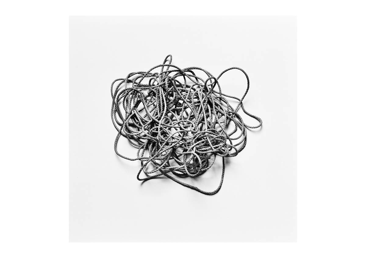 Still life of a tangled ball of raffia yarn on a white background, from the series I will be around by Emmanuel Pineau