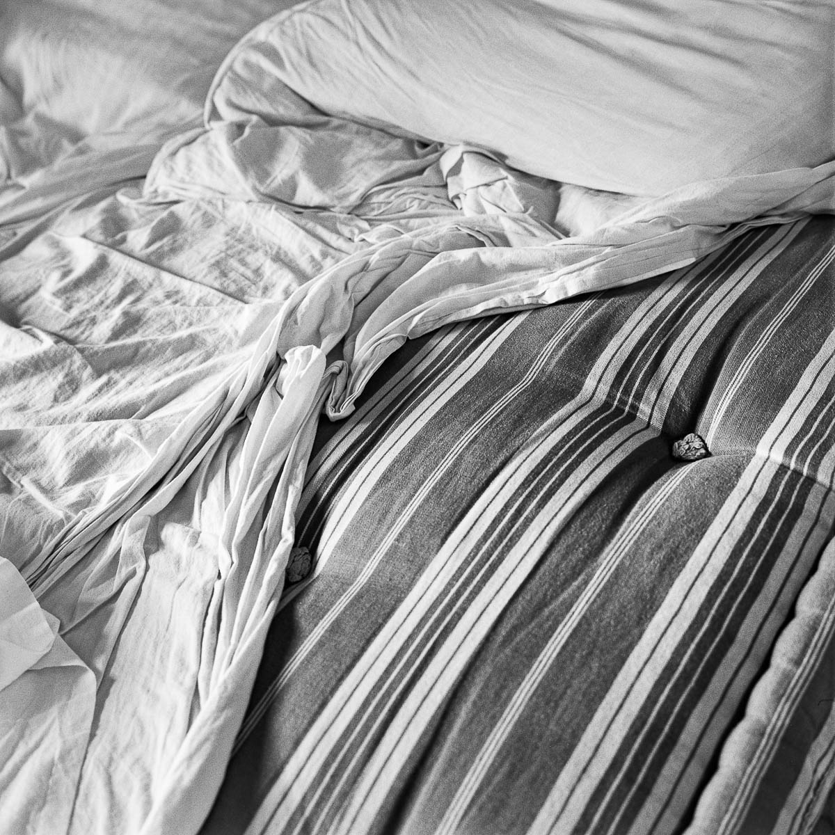 The unmade bed in the morning light, from the series Les limites du territoire by Emmanuel Pineau