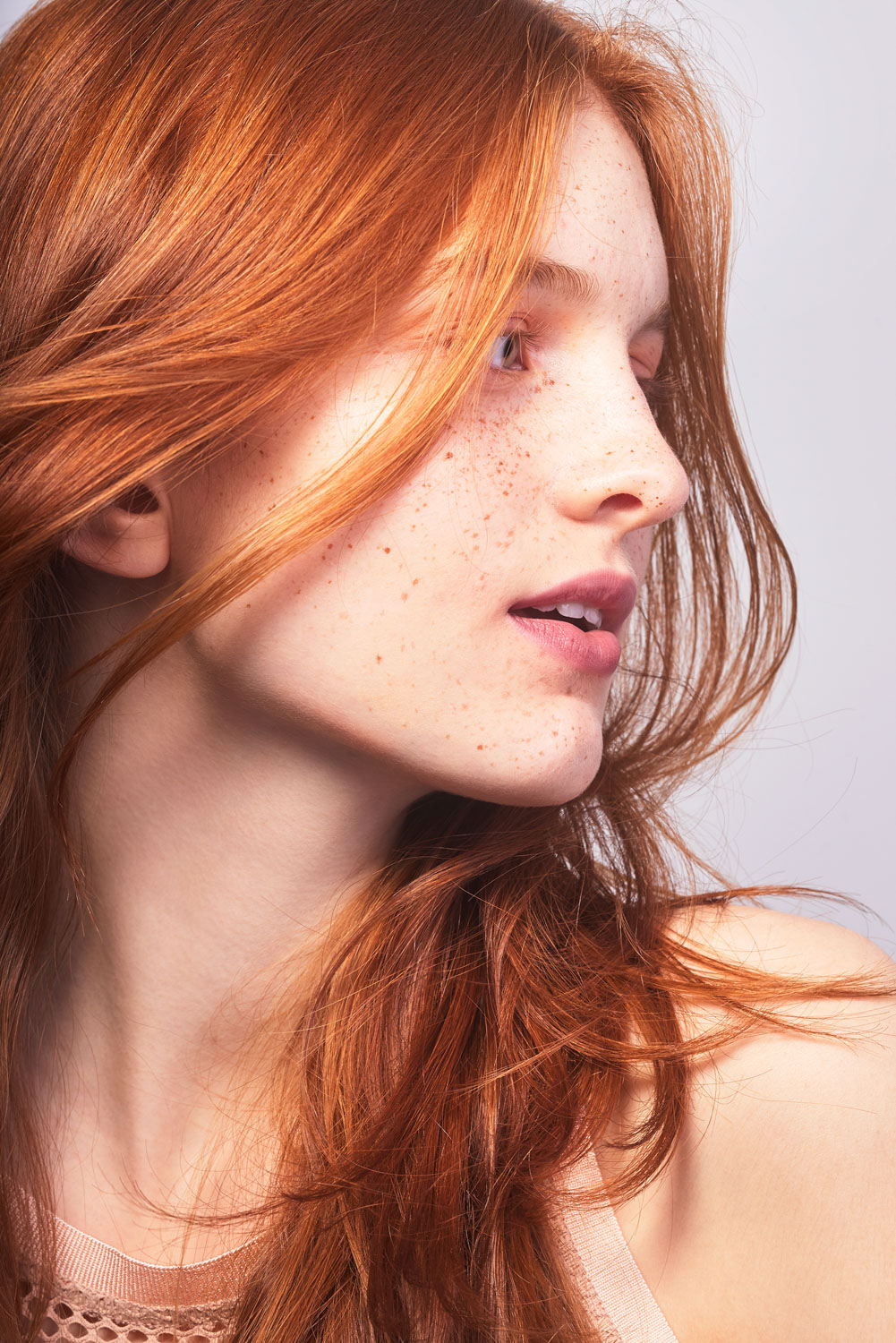 Close up of a Caucasian model's face with natural skin texture and long red hair by Sophie Delaporte
