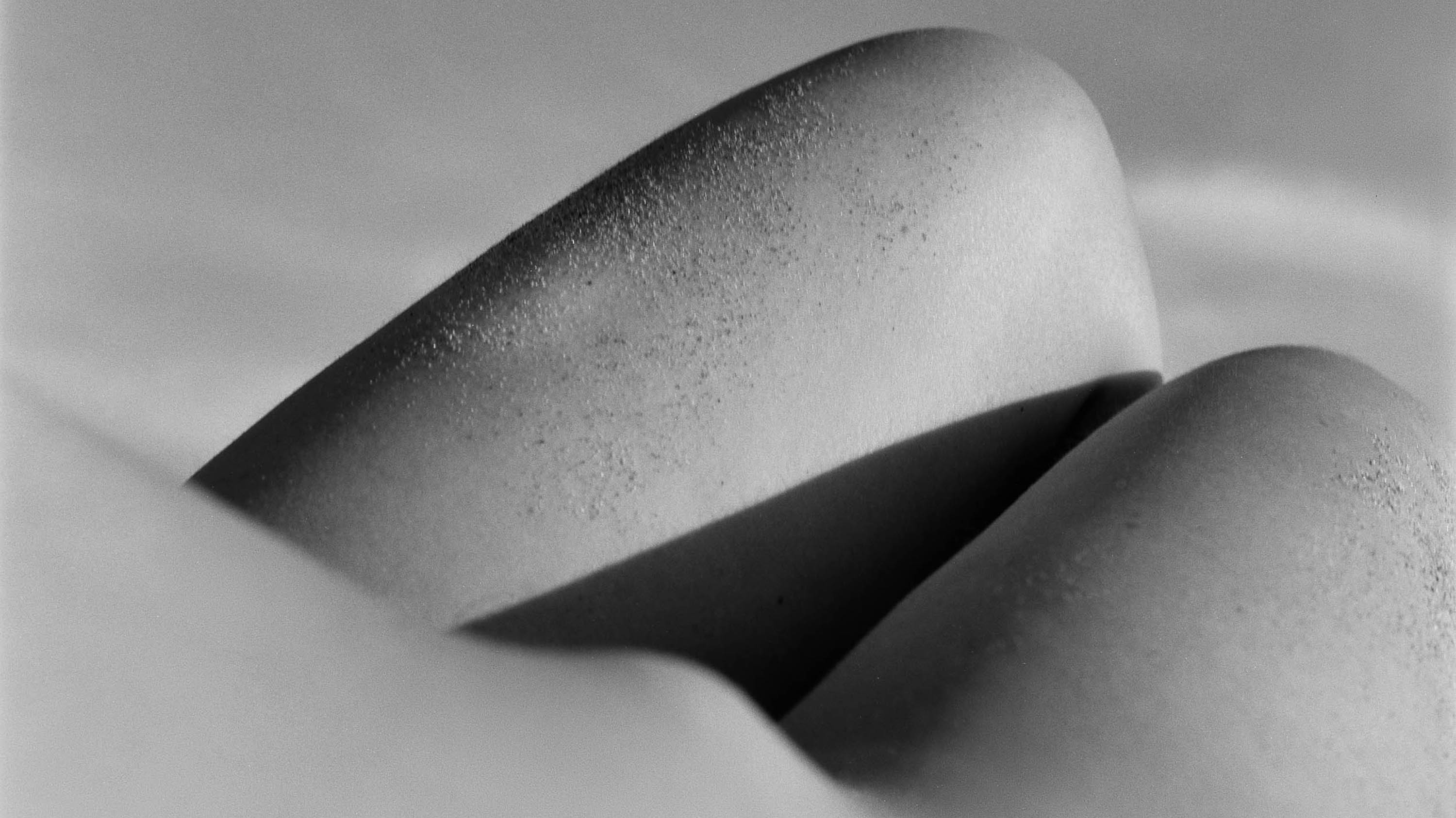 Close-up of a woman's body lying naked on a beach in summer, black and white analog photography from the series One piece of my mind by Emmanuel Pineau
