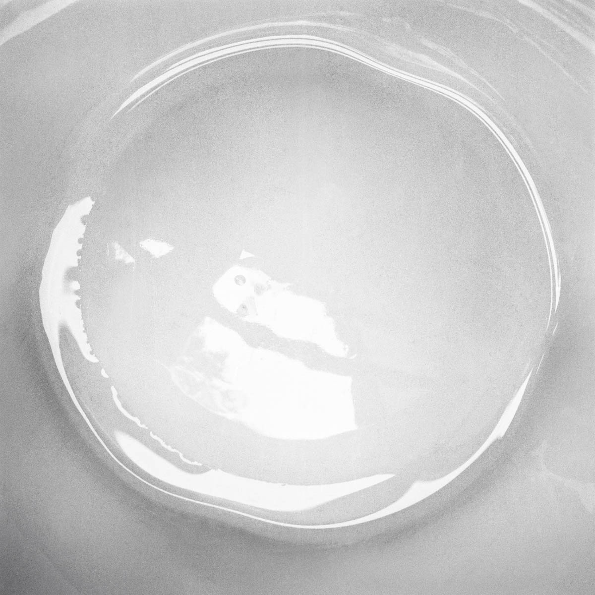 The bottom of a white porcelain dish photographed in extreme close-up, from the series One piece of my mind by Emmanuel Pineau