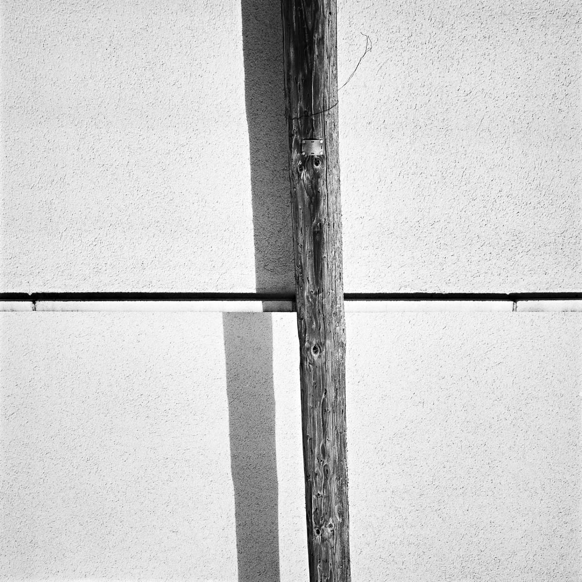 Abstract composition with an electric pole in front of a white wall, from the series One piece of my mind by Emmanuel Pineau