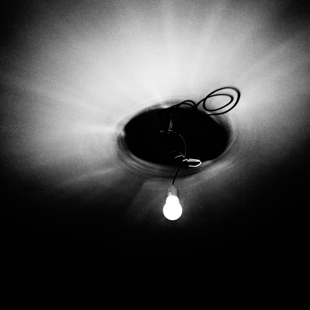 A bare lightbulb hanging from the ceiling, from the series One piece of my mind by Emmanuel Pineau