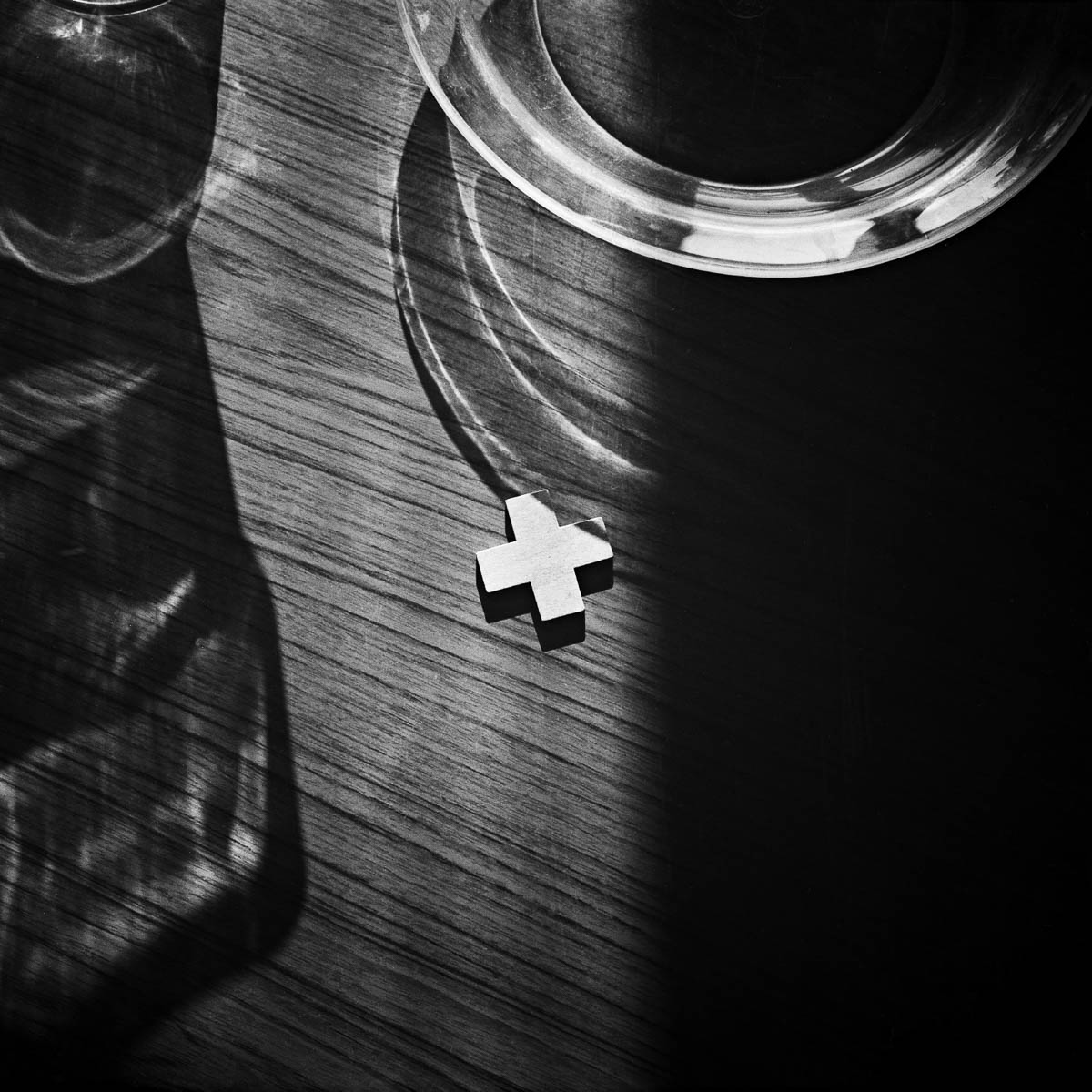 Composition with glass objects and a wooden cross in sunlight, from the series One piece of my mind by Emmanuel Pineau