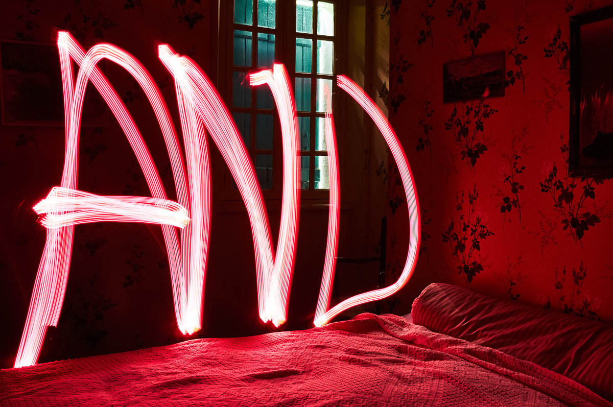 Vintage bedroom with the word AND written in red light painting above the bed, from the series Out of disorders by Emmanuel Pineau