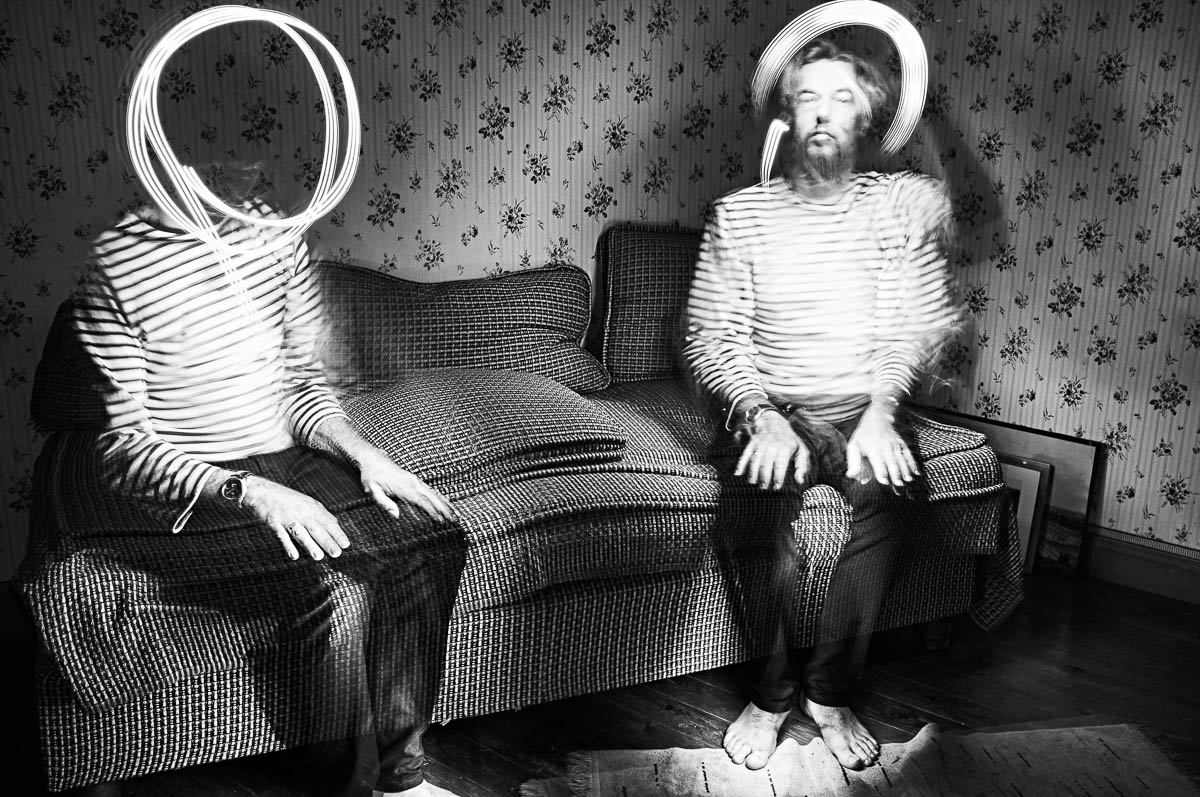 Double self-portrait of Emmanuel Pineau sitting on a vintage sofa with light painting effects, from the series Out of disorders by Emmanuel Pineau