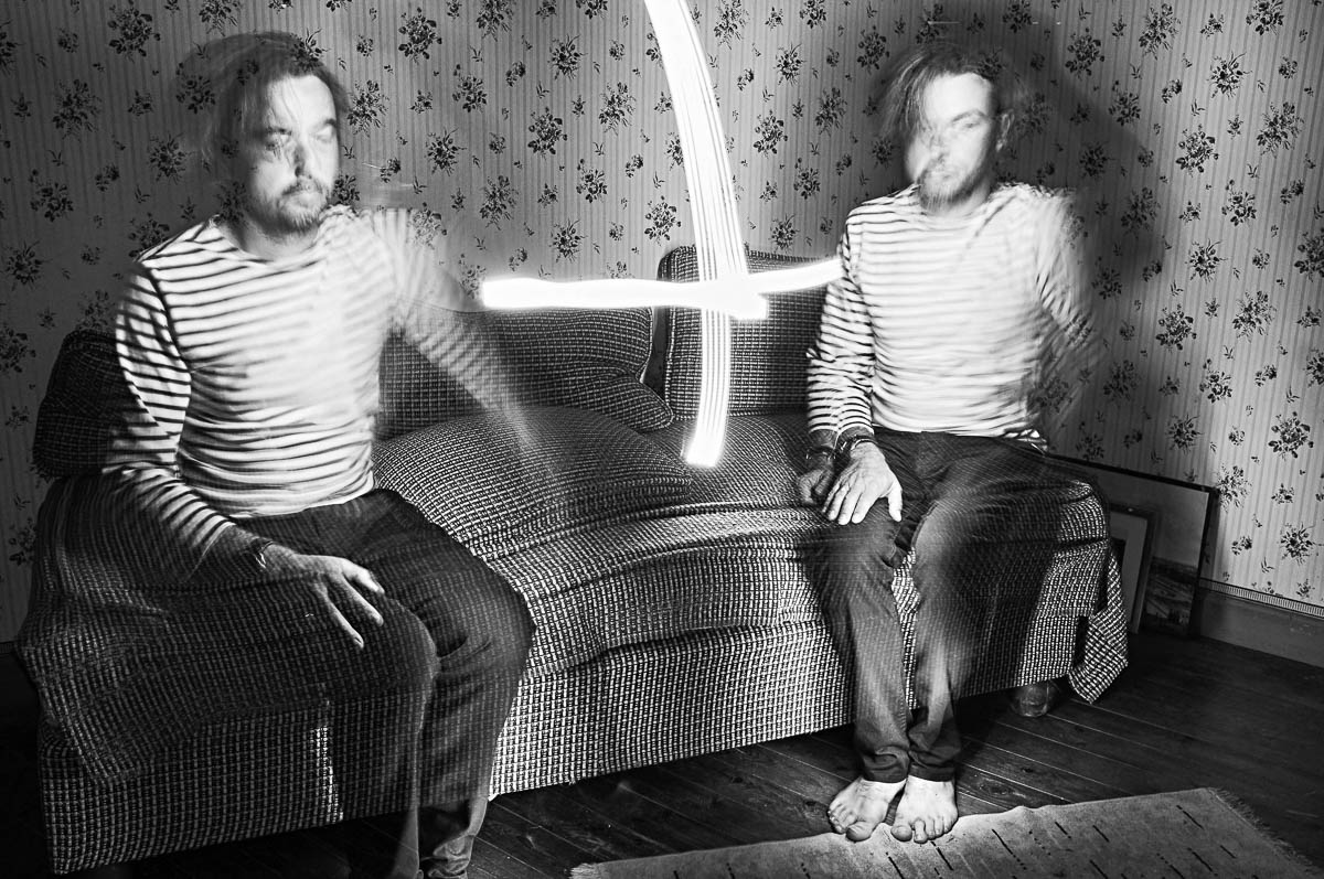 Double self-portrait of Emmanuel Pineau sitting on a vintage sofa with light painting effects, from the series Out of disorders by Emmanuel Pineau