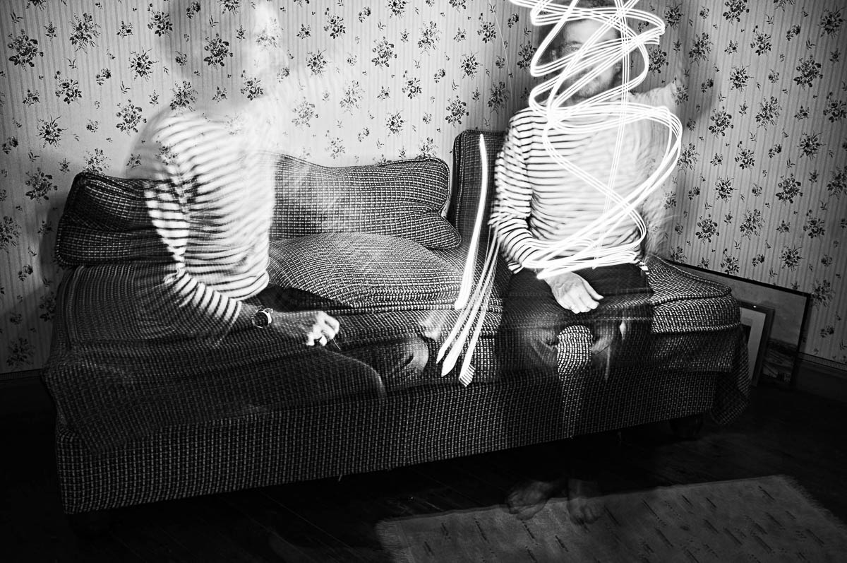 Double self-portrait of Emmanuel Pineau sitting on a vintage sofa with light painting effects, from the series Out of disorders by Emmanuel Pineau